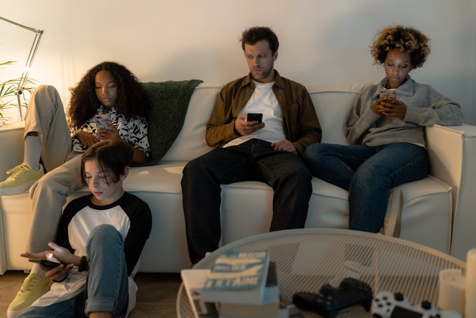 A family relaxing together on a couch in warm evening light, one parent glancing at an iPhone