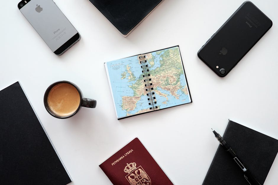 A flat lay with a smartphone showing a calendar app, a passport, and a coffee cup on a wooden surface