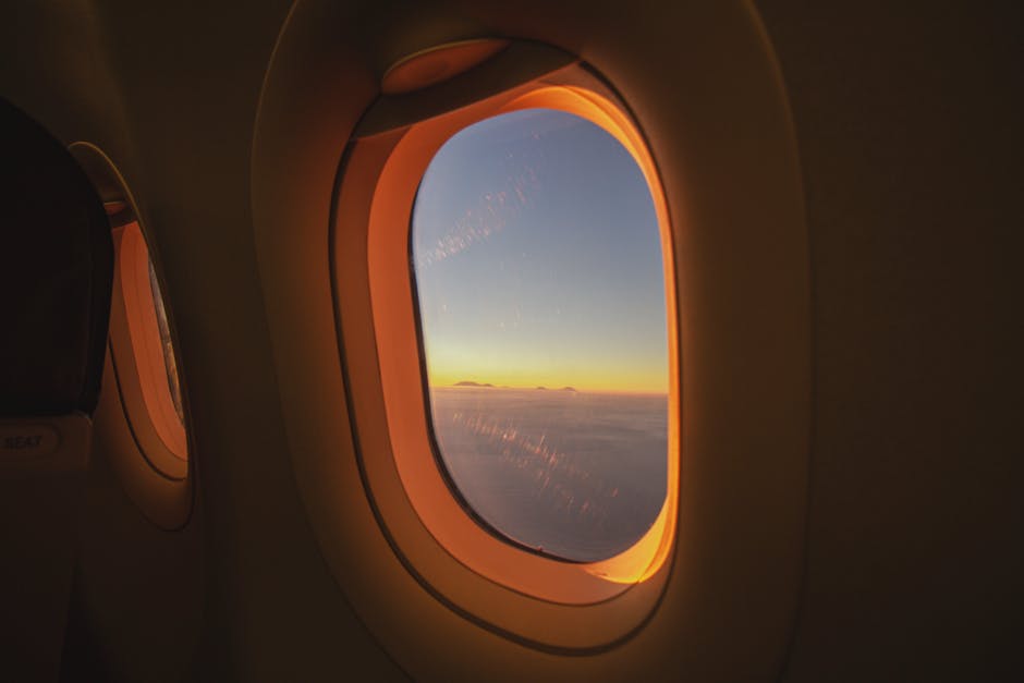 A passenger's view from an airplane window seat looking out at clouds and blue sky