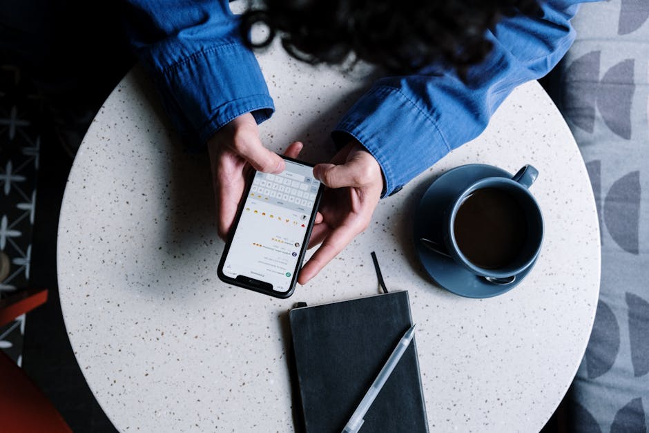 A woman looking at her iPhone screen at a coffee shop table with a latte in soft morning light