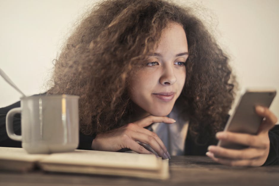 A person sitting cross-legged on a bed looking calmly at their phone in warm afternoon light
