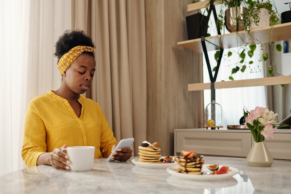 A person sitting by a window in soft natural light, relaxed, looking at their phone with a small smile