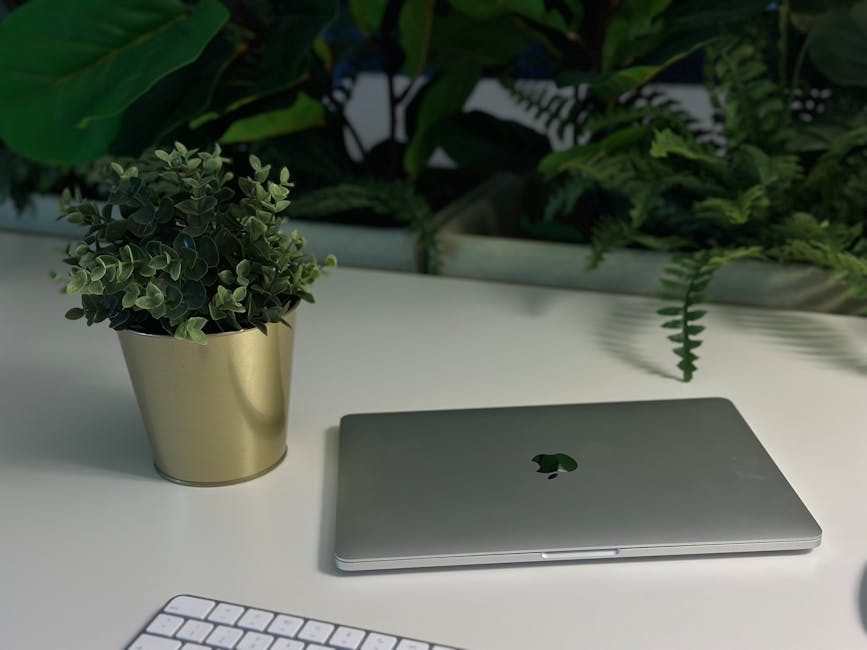 A minimal home desk with plants, soft natural light, and a clean workspace with a phone and notebook