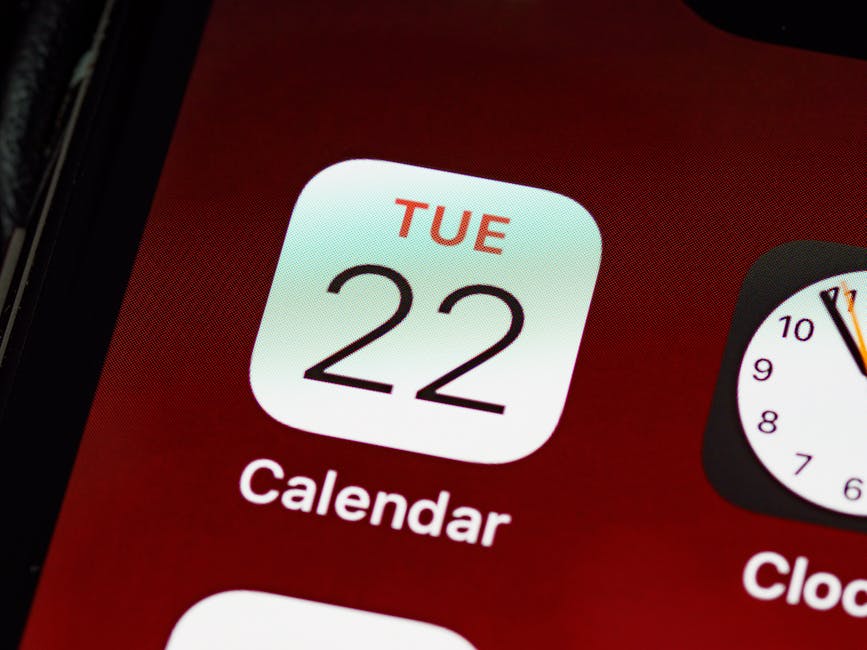 A smartphone showing a calendar app open on a clean wooden desk in natural light