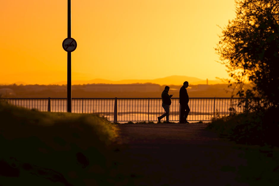 Two people walking together on a city sidewalk in warm golden evening light