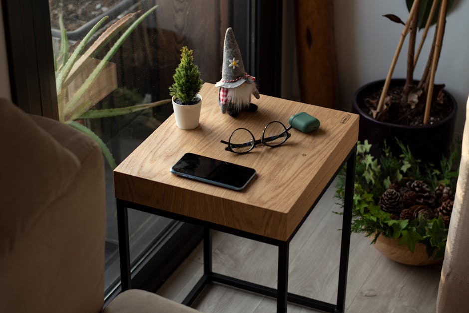 A minimal wooden desk with a small plant, a phone, and a mug in soft morning light