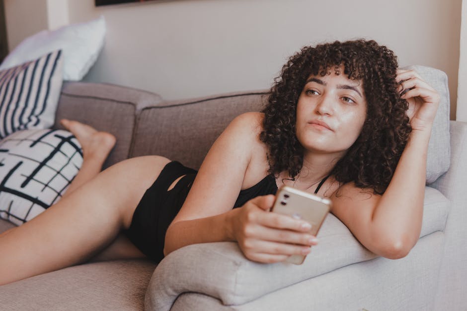 A woman relaxing on a couch holding her phone in warm afternoon light