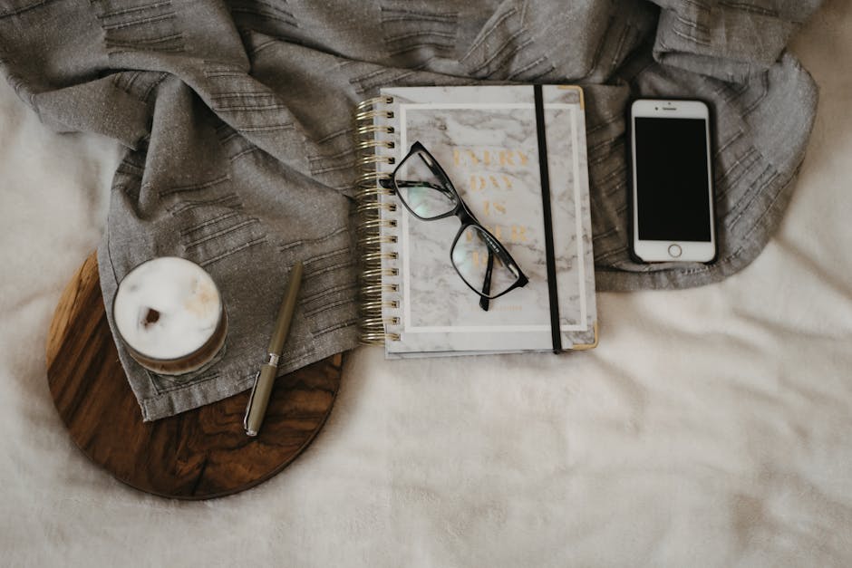 A calm morning scene with a person writing in a notebook next to an iPhone and a mug of coffee