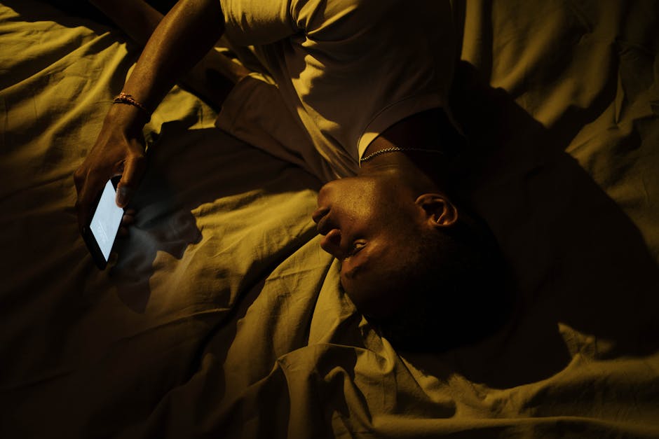 A person glancing at their phone in soft evening light, relaxed on a couch