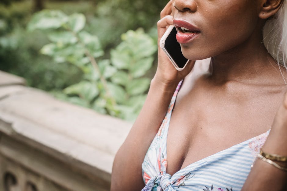 A person speaking into their phone while walking outside in warm afternoon light