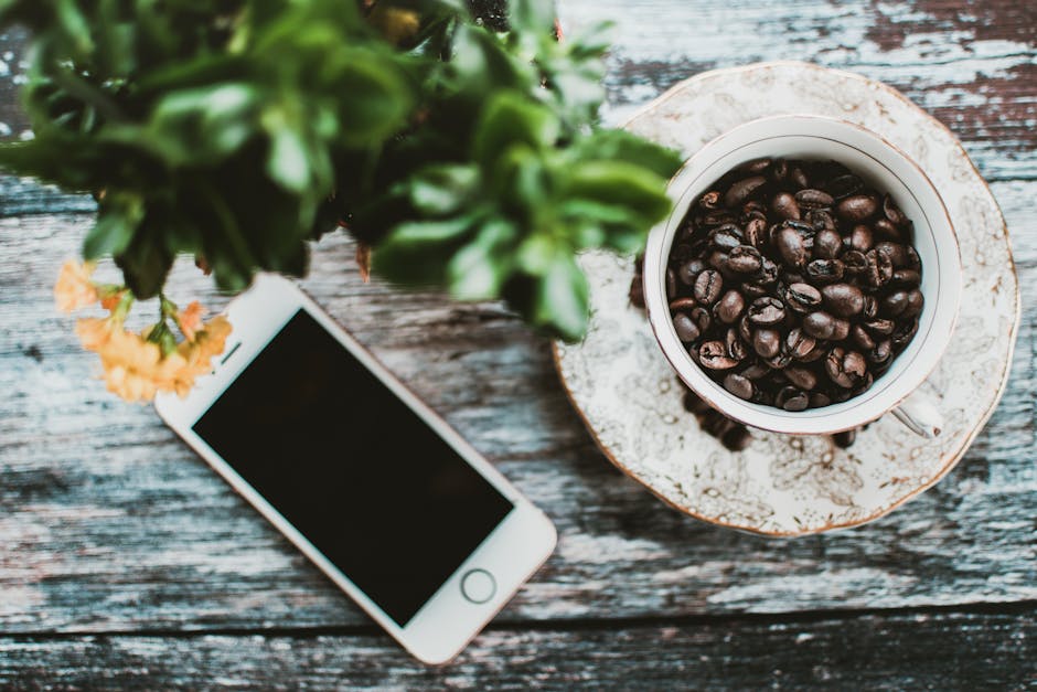 A phone resting on a kitchen counter beside a coffee cup in early morning light