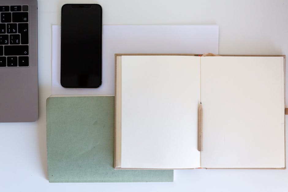 An overhead view of a clean desk with a single notebook, a cup of tea, and a phone showing a simple calendar