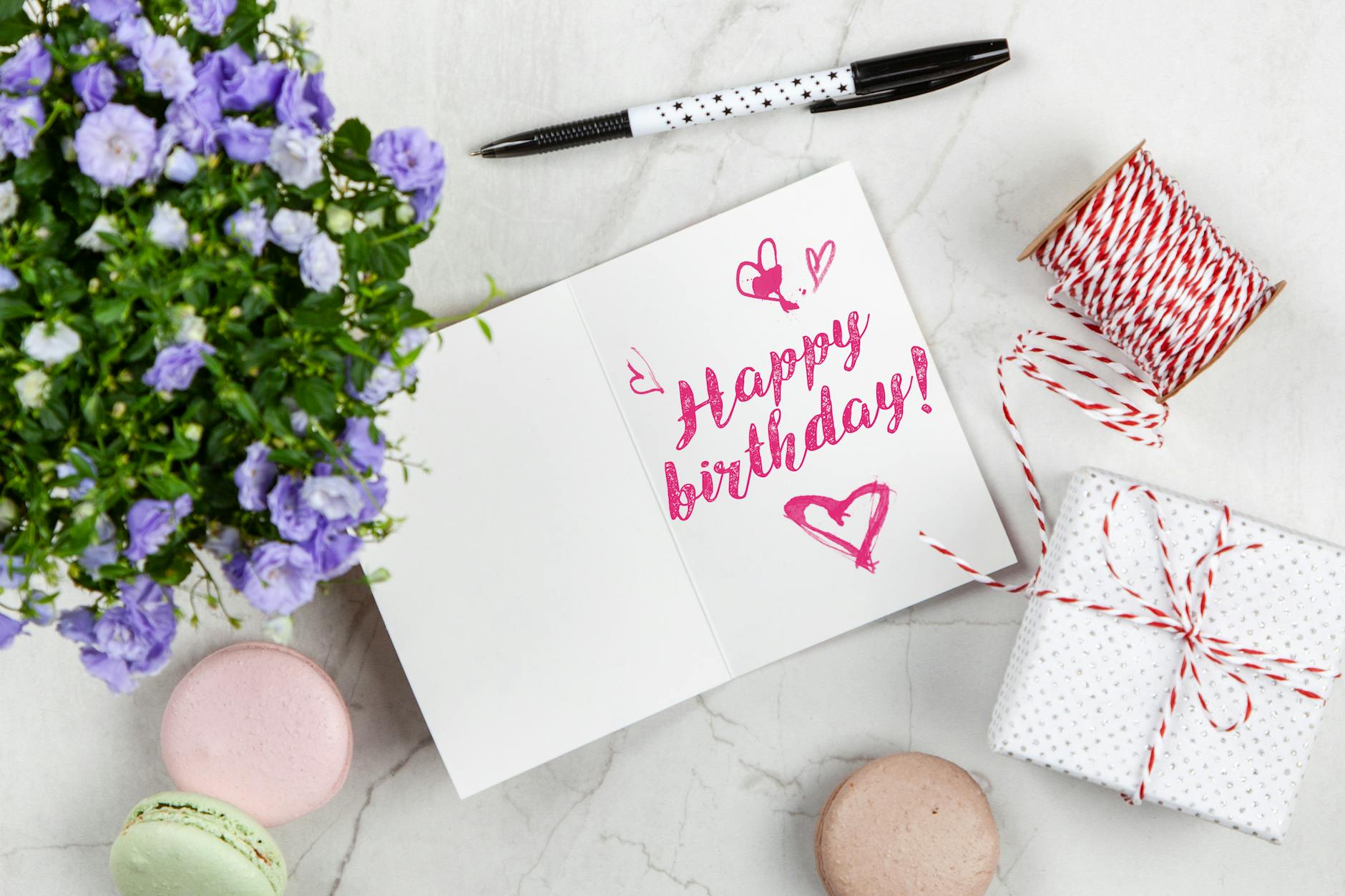 A hand writing inside a birthday card at a clean kitchen table, soft natural light from a window