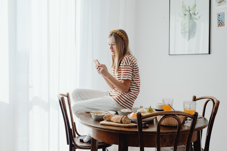 A woman looking at her phone with a calm expression in soft natural window light